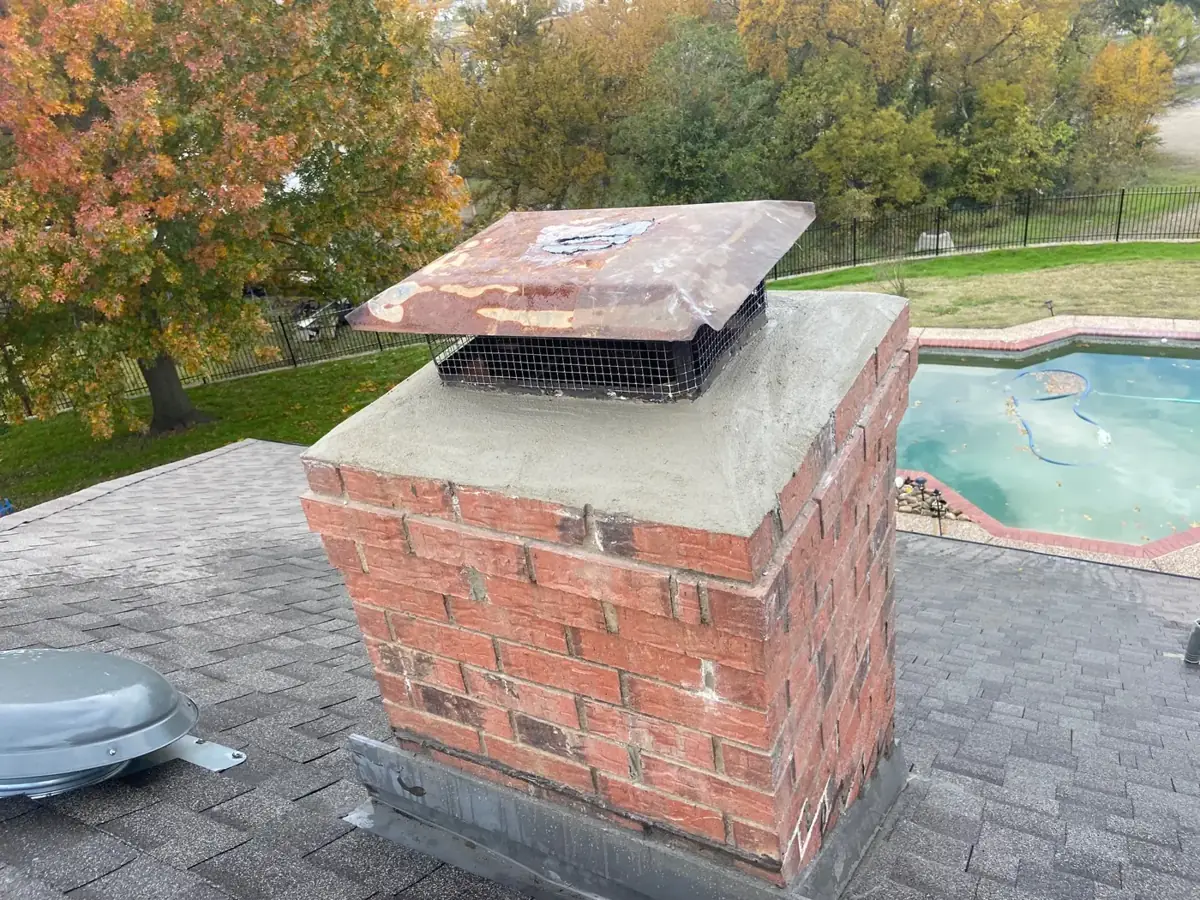 Rebuilt red brick chimney with a copper cap above a backyard pool