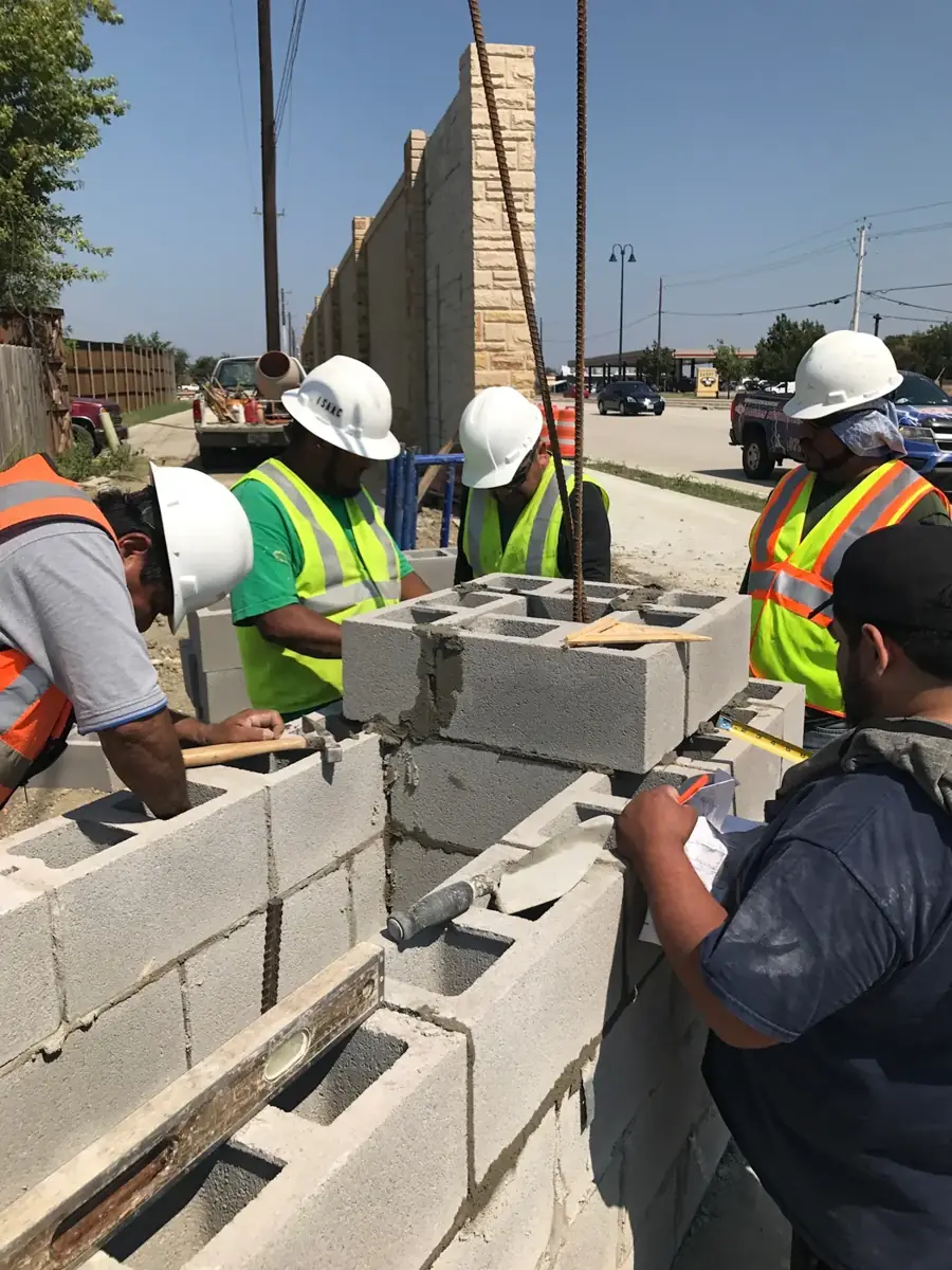 Crew in hard hats setting CMU block with rebar at a commercial site